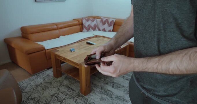 Man opens his empty wallet in despair, highlighting financial struggles and economic hardship with no money left.