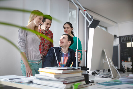 Colleagues smile and collaborate on a computer at the office