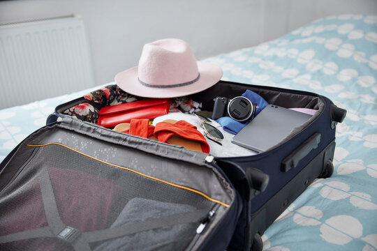 Suitcase with summer vacation utensils on bed