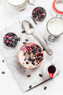 Bowl of vegan coconut yogurt with berries, puffed amaranth, pumpkin seeds and raspberry pulp