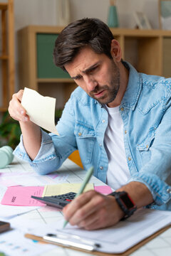 Stressed person calculating bills and finances at home
