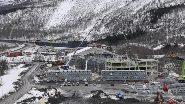 Narvik, Nordland - 09 July 2026: View of the data center construction site in Narvik with cranes, modular office units, and snow-covered mountains in the background.