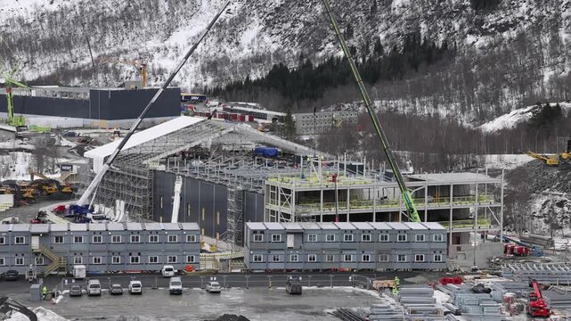 Narvik, Nordland, Norway - 09 July 2026: View of the data center construction site with cranes, modular buildings, and snow-covered mountains in the background.