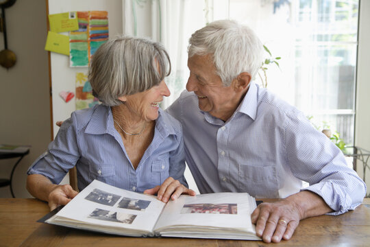 Germany, Bavaria, Senior couple with photo album, smiling