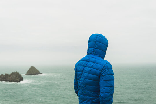 France, Bretagne, Finistere, Crozon peninsula, man standing at the coast with hooded jacket