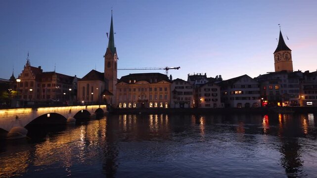 View of Fraumunster church and Limmat river at twilight with city lights reflecting on the water in Zurich, Zurich, Switzerland.