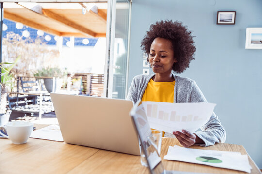 Smiling woman reviews documents at her home office desk