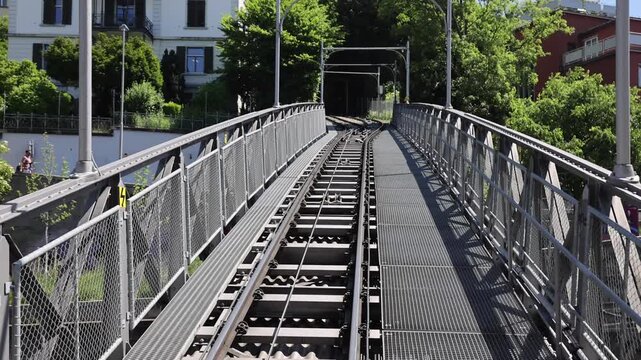 View of the historic Polybahn funicular railway tracks leading towards a tunnel, surrounded by urban buildings and lush trees in Zurich, Zurich, Switzerland.