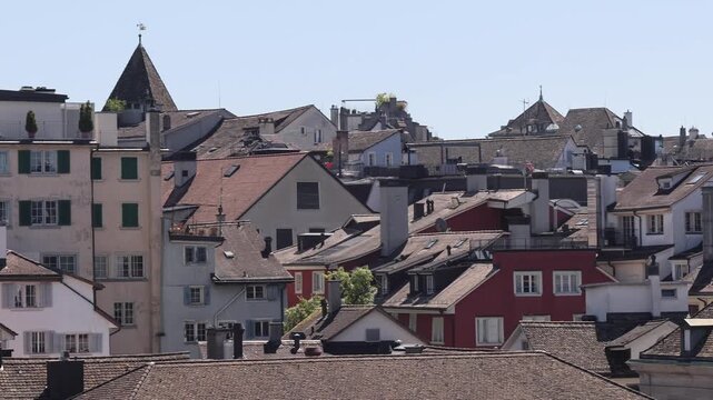 View of historic rooftops in the Old Town of Zurich, Switzerland, featuring traditional tiled roofs, chimneys, and white building facades under a clear sky in Zurich, Zurich, Switzerland.