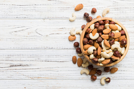 Assortment of nuts in wooden bowl on colored table. Cashew, hazelnuts, walnuts, almonds. Mix of nuts Top view with copy space