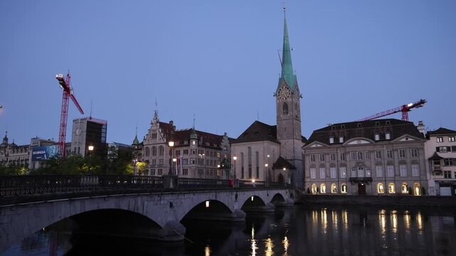 View of the historic Fraumunster church and stone bridge over the Limmat river at dusk in Zurich, Zurich, Switzerland.