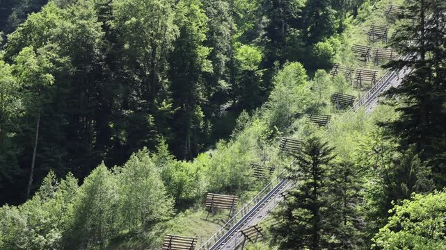 View of the steep Stoosbahnen funicular railway climbing the lush green hillside in Schwyz, Schwyz, Switzerland.