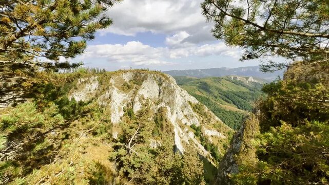 Scenic mountain view of rugged cliffs and green valleys framed by pine trees