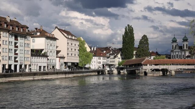 View of the historic Jesuit Church and the Reuss river with traditional buildings along the waterfront in Lucerne, Lucerne, Switzerland.