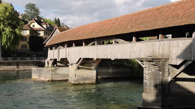 View of the historic wooden Chapel Bridge spanning the Reuss River with traditional buildings in the background in Lucerne, Lucerne, Switzerland.