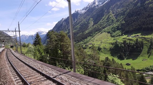 View of Gotthard Panorama Express SBB traveling through the Swiss Alps with pine forests and mountain peaks in Lugano, Ticino, Switzerland.
