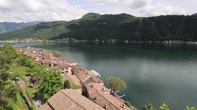 View of Morcote village with its historic terracotta rooftops nestled along the shores of Lake Lugano in Morcote, Ticino, Switzerland.