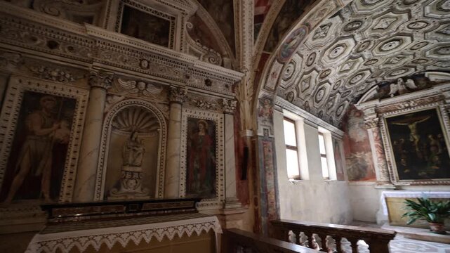 View of the ornate altar with intricate frescoes and stone carvings inside a historic church in Morcote, Ticino, Switzerland.