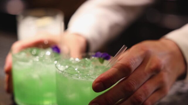 Bartender working, beautiful row line of different coloured liquor alcohol cocktails on a party in a bar, catering banquet on event, barman mixing drinks, selection of beverages in a restaurant club