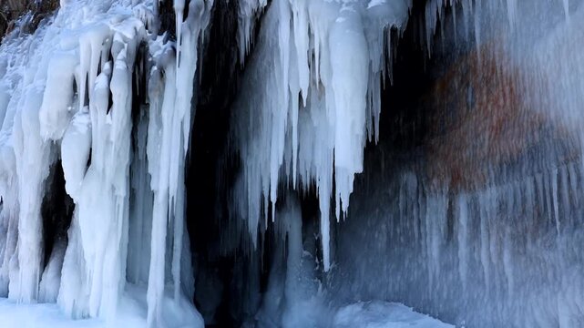 View of the frozen ice cave at Lake Baikal with hanging icicles and snow-covered rock formations in Khuzhir, Irkutsk Oblast, Russia.