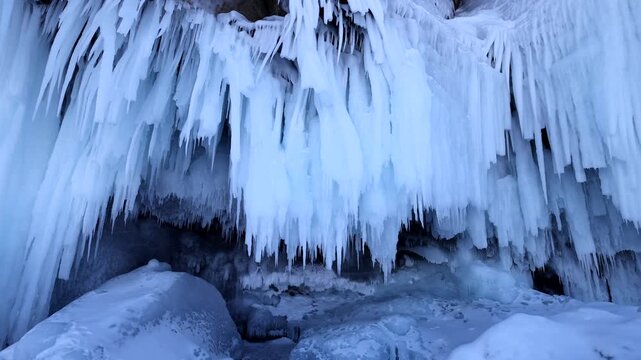 View of the frozen ice cave at Lake Baikal with hanging icicles and snow-covered rocks in Khuzhir, Irkutsk Oblast, Russia.