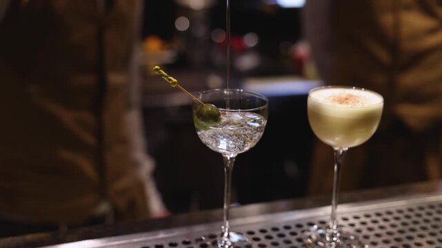 Bartender working, beautiful row line of different coloured liquor alcohol cocktails on a party in a bar, catering banquet on event, barman mixing drinks, selection of beverages in a restaurant club