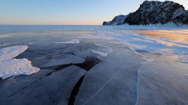 View of frozen Lake Baikal ice sheets with snow and clear sky in Khuzhir, Irkutsk Oblast, Russia.