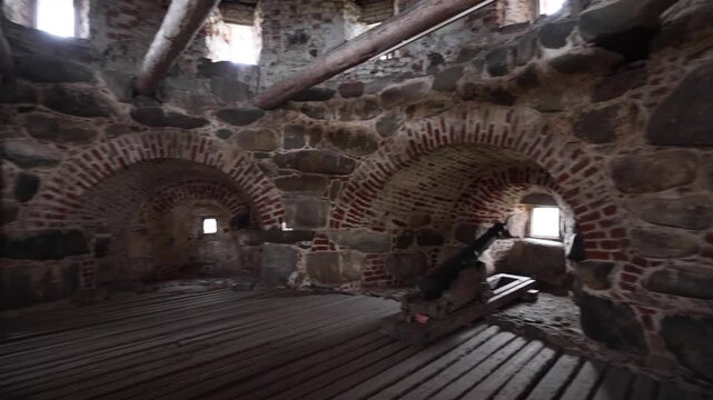 View of the historic stone and brick interior of the Solovetsky Monastery fortifications featuring an old cannon on a wooden floor in Solovetsky, Arkhangelsk Oblast, Russia.