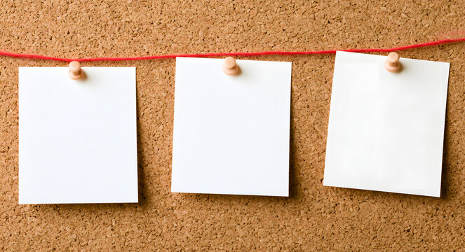 Three notes without text stuck to a corkboard with red string and metal pins
