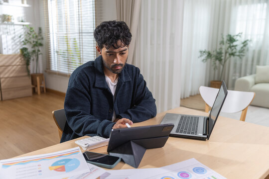 man working from home using tablet and laptop at desk, digital technology, remote work, online business, productivity, communication, freelance lifestyle.