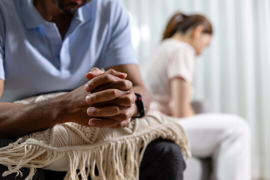 Relationship conflict concept. Distressed couple sits apart at home after an argument, showing emotional distance and communication problems. Conflict, couple, relationship, stress, communication.