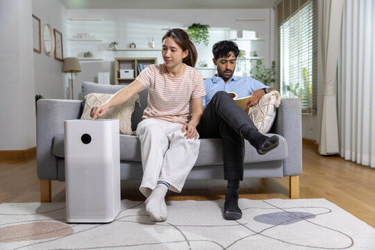 Air purifier concept. couple relaxes on sofa while using air purifier at home, supporting clean indoor air and healthy living. Air purifier, couple, home, clean.