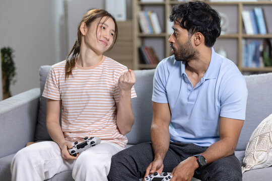 Gaming winner concept. woman celebrates winning video game while playing with man on a sofa at home. Gaming, victory, couple, competition, celebration.