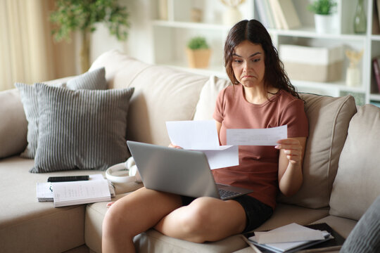 Perplexed teenage girl reading paper letter at home