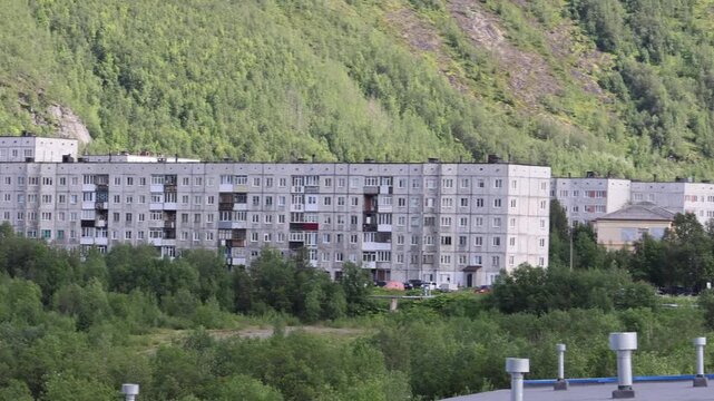 View of apartment buildings surrounded by dense green forest in Kirovsk, Murmansk Oblast, Russia.