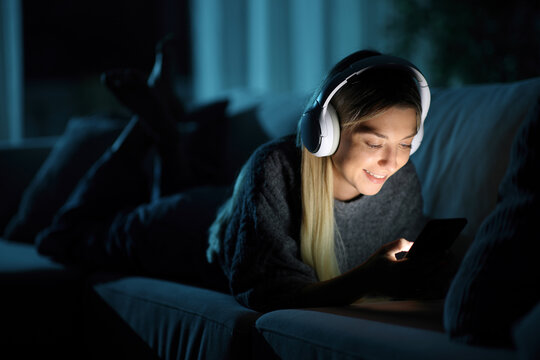 Happy woman wathing media on smart phone in the night