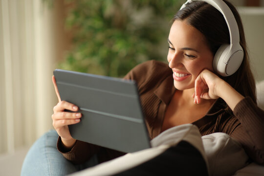 Happy woman wearing headphone and using tablet at home
