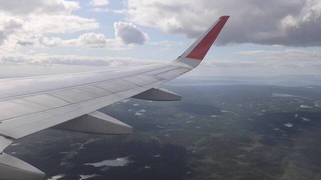 View of an airplane wing flying over the vast forested landscape and lakes near Kirovsk, Murmansk Oblast, Russia.