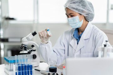Fototapeta premium Young asian female scientist examining laboratory sample for medical research, biotechnology testing and scientific analysis