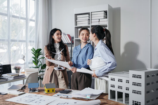 Asian Women Architects Team Reviewing Building Blueprint and Win