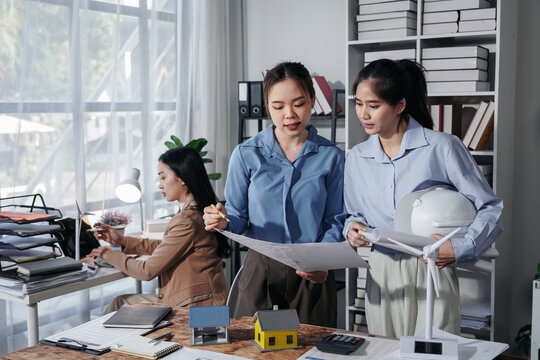 Asian Women Architects Reviewing Blueprint in Office Meeting for