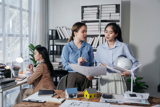 Asian Women Architects Discussing Blueprint in Office Meeting Co