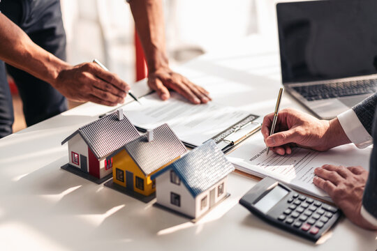 Real estate professional and client reviewing property contract and mortgage documents for home purchase and financing in office