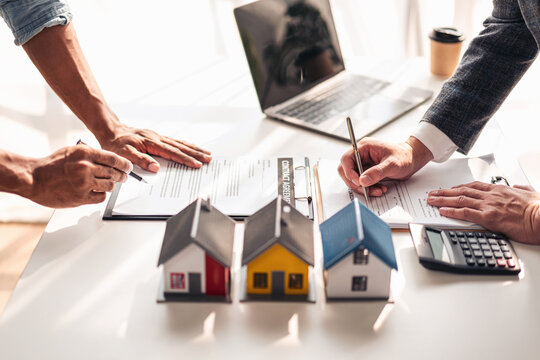 Real estate professional and client reviewing property contract and mortgage documents for home purchase and financing in office