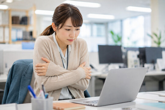 肌寒いオフィスで腕を抱えて寒さを感じる女性　職場の冷えと寒暖差