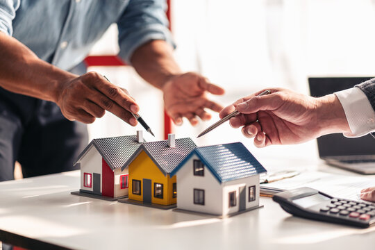 Real estate professional and client reviewing property contract and mortgage documents for home purchase and financing in office