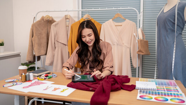 Young asian fashion designer working on digital fashion illustration with tablet