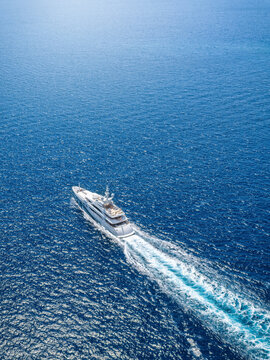 Aerial view of an ultra modern luxury yacht cruising over sparkling ocean with speed