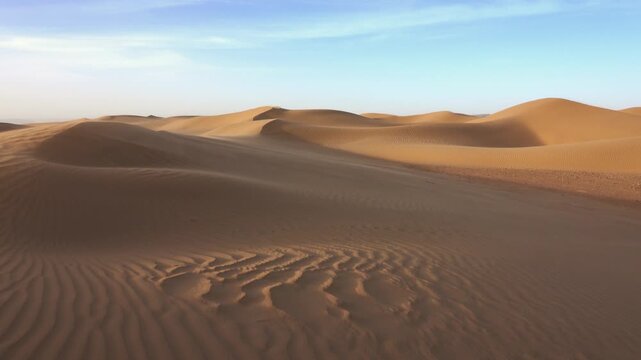 View of the Sahara Desert with rolling sand dunes under a clear blue sky in MOROCCO.