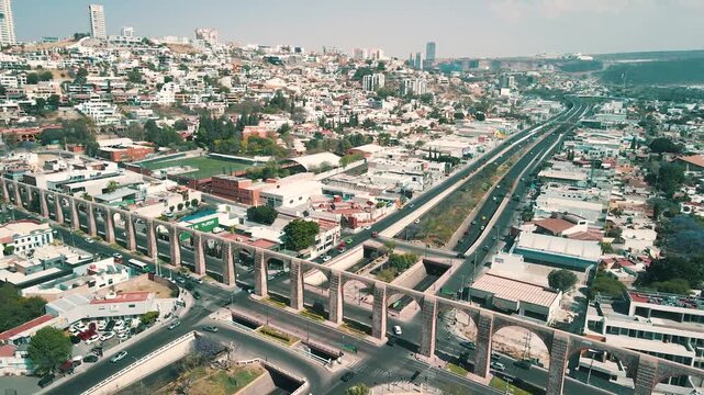 Aerial drone shot of historic stone aqueduct in Queretaro city Mexico with busy traffic and urban sprawl.
